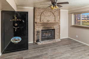 Unfurnished living room with dark hardwood / wood-style floors, a textured ceiling, and a brick fireplace