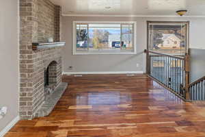 Interior space with a fireplace, ornamental molding, a textured ceiling, and hardwood / wood-style flooring