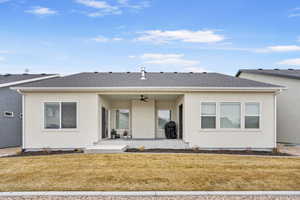 Back of property featuring ceiling fan, roof with shingles, a lawn, and stucco siding