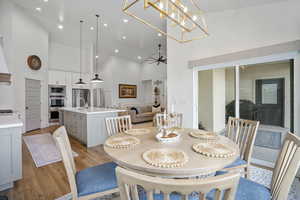 Dining space with high vaulted ceiling, recessed lighting, ceiling fan, and light wood finished floors