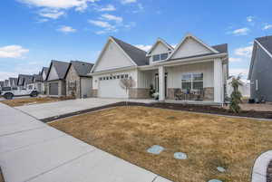 View of front of home with driveway, a garage, a residential view, a porch, and board and batten siding