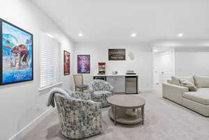 Interior space with a dry bar, light carpet, baseboards, and recessed lighting