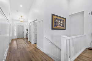 Foyer entrance with a chandelier, a high ceiling, wood finished floors, visible vents, and baseboards