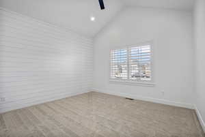 Spare room with high vaulted ceiling, carpet flooring, visible vents, and baseboards