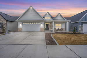 View of front facade with board and batten siding, concrete driveway, brick siding, and a garage