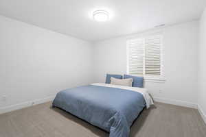 Bedroom with light carpet, visible vents, and baseboards