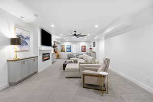 Living area featuring light colored carpet, a glass covered fireplace, visible vents, and recessed lighting