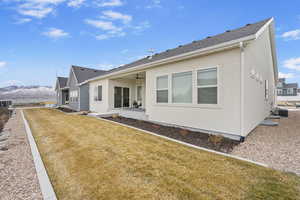 Back of property featuring a yard, stucco siding, fence, a mountain view, and ceiling fan