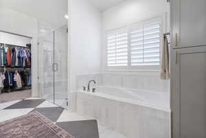 Bathroom featuring a spacious closet, a stall shower, and a bath