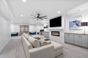 Living area with light carpet, visible vents, a glass covered fireplace, and recessed lighting