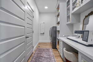 Office featuring light wood finished floors, washer and clothes dryer, recessed lighting, and baseboards