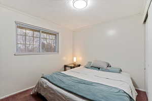 Bedroom featuring dark colored carpet, ornamental molding, and a textured ceiling