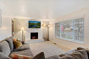 Carpeted living room with a fireplace and a textured ceiling