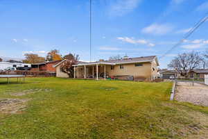 Rear view of property with a lawn and a trampoline