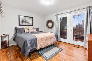 Bedroom with access to exterior, french doors, and wood-type flooring