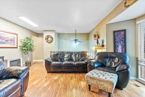 Living room featuring ceiling fan, light wood-type flooring, and a wealth of natural light