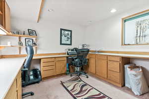 Carpeted home office featuring built in desk and sink