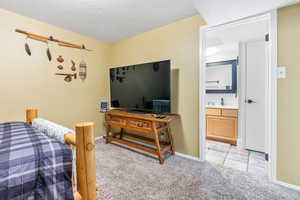 Carpeted bedroom featuring a textured ceiling and connected bathroom