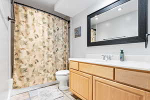 Bathroom with a shower with shower curtain, vanity, and toilet