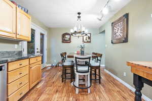 Dining room featuring a textured ceiling, an inviting chandelier, light hardwood / wood-style flooring, and track lighting