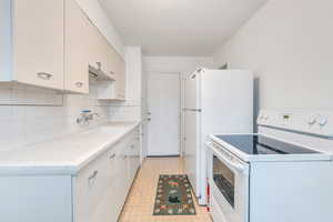 Kitchen featuring decorative backsplash, sink, and white appliances