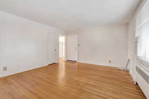 Spare room featuring radiator heating unit and light hardwood / wood-style floors