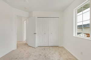 Unfurnished bedroom with light carpet and a closet