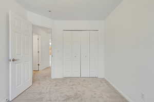 Unfurnished bedroom with light colored carpet and a closet