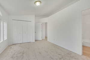 Unfurnished bedroom with light carpet and a closet