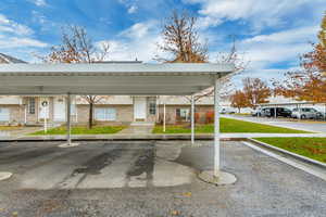 View of parking with a yard and a carport