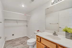 Bathroom with hardwood / wood-style floors, vanity, and toilet