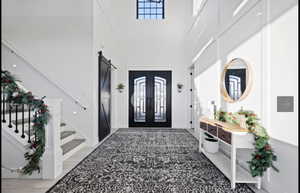 Entrance foyer with a barn door, a towering ceiling, and french doors