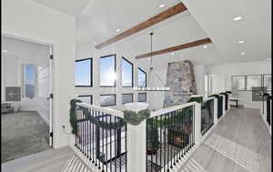 Hallway with lofted ceiling with beams, light hardwood / wood-style floors, and an inviting chandelier