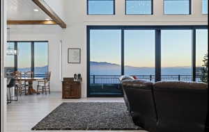 Living room with beamed ceiling, a water view, and light wood-type flooring