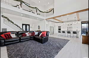 Living room featuring beam ceiling, an inviting chandelier, a towering ceiling, and french doors