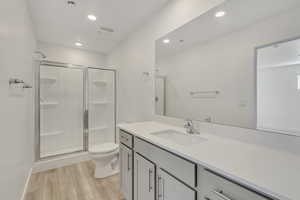 Bathroom featuring vanity, hardwood / wood-style flooring, toilet, and walk in shower