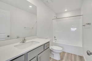 Full bathroom featuring washtub / shower combination, toilet, wood-type flooring, and vanity