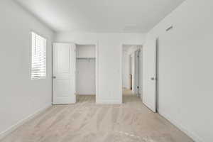 Spacious bedroom featuring a walk in closet, light carpet, and a closet