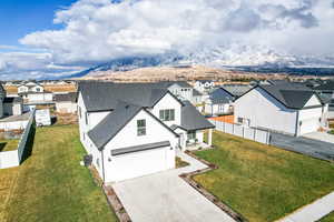 View of front of property featuring a mountain view, a front yard, and a garage