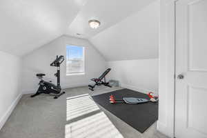 Workout room with a textured ceiling, light colored carpet, and lofted ceiling