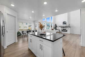 Kitchen with light hardwood / wood-style floors, white cabinetry, plenty of natural light, and a kitchen island