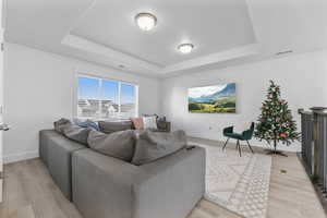 Living room with a raised ceiling and light wood-type flooring