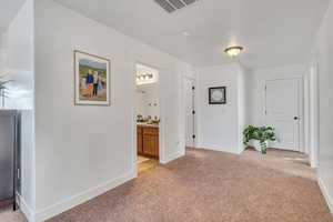 Corridor with sink and light colored carpet