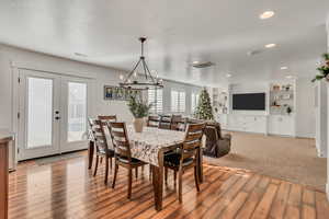 Dining area featuring french doors, built in features, a notable chandelier, and light hardwood / wood-style flooring