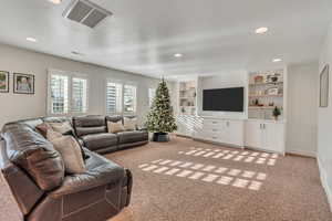 Carpeted living room with built in shelves