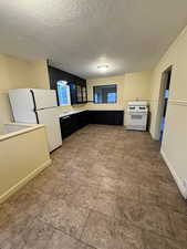 Kitchen featuring a textured ceiling and white appliances