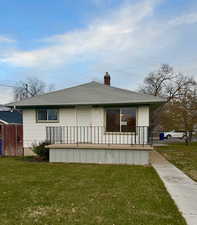 Back of property featuring a yard and covered porch