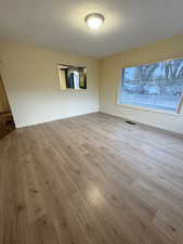 Unfurnished room with light wood-type flooring and a textured ceiling