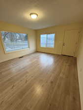 Unfurnished room featuring plenty of natural light, a textured ceiling, and light wood-type flooring