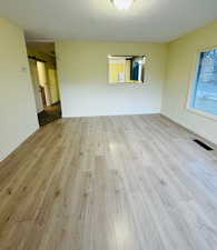 Unfurnished room with a textured ceiling, a barn door, and light hardwood / wood-style floors